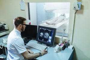 Médico observando paciente fazendo uma tomografia computadorizada.