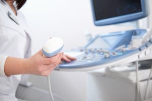 Profissional da saúde segurando um aparelho de ultrassom.